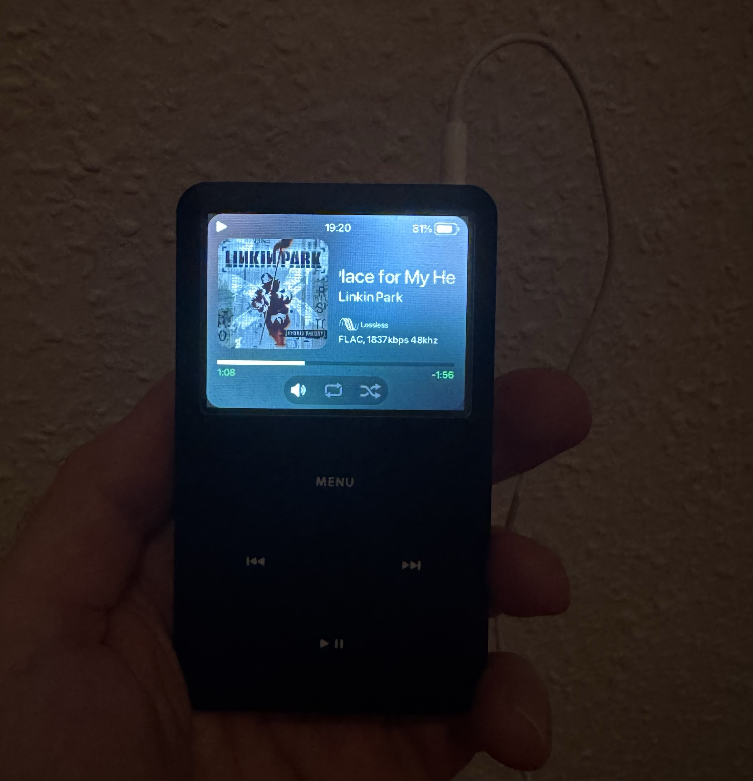 An iPod Classic with a custom Rockbox OS, displaying a song playing.